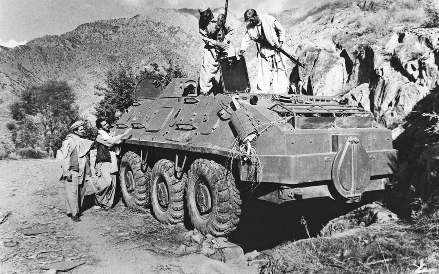 FILE - In this Dec. 27, 1979, file photo, rebel Muslim fighters inspect a Soviet tank captured in fighting with the Kabul government forces on near Asmar, Afghanistan. The Soviet Union invaded Afghani ...