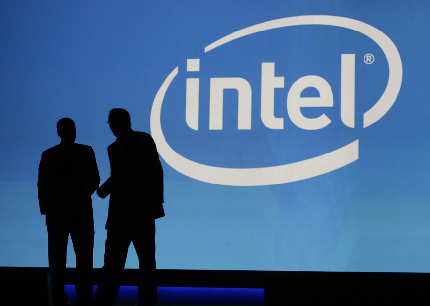 FILE - In this Jan. 7, 2010, file photo, people are silhouetted in front of the Intel sign at the International Consumer Electronics Show (CES) in Las Vegas. Microchip maker Intel is buying chip desig ...
