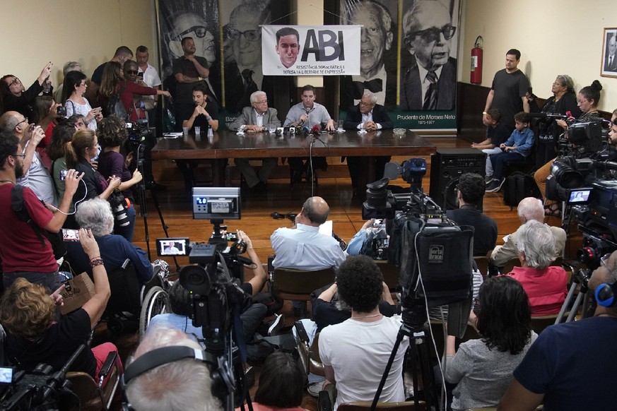 Journalist Glenn Greenwald, speaking into microphone, takes part in a press conference before the start of a protest in his support in front of the headquarters of the Brazilian Press Association, kno ...
