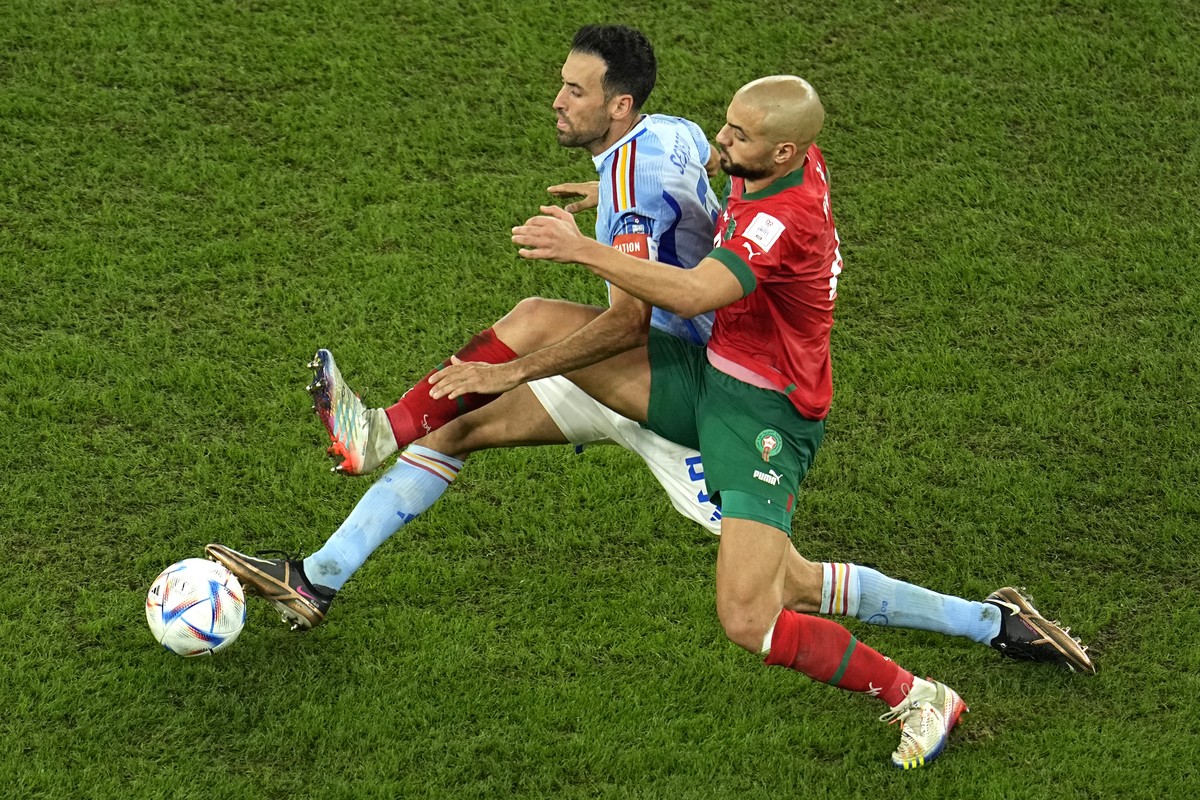 Spain's Sergio Busquets, left, challenges for the ball with Morocco's Sofyan Amrabat during the World Cup round of 16 soccer match between Morocco and Spain, at the Education City Stadium in ...