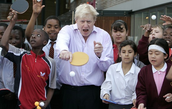 FILE - In this Friday, June 25, 2010 file photo, Mayor of London Boris Johnson, center, poses for photographers as he plays a game of table tennis with pupils in London. (AP Photo/Akira Suemori, File)