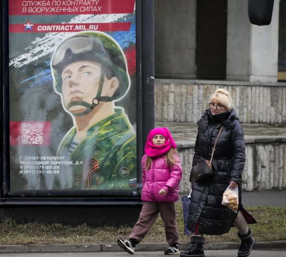 People walk past an army recruiting billboard with the words &quot;Military service under contract in the armed forces&quot; in St. Petersburg, Russia, Friday, March 24, 2023. A campaign to replenish  ...