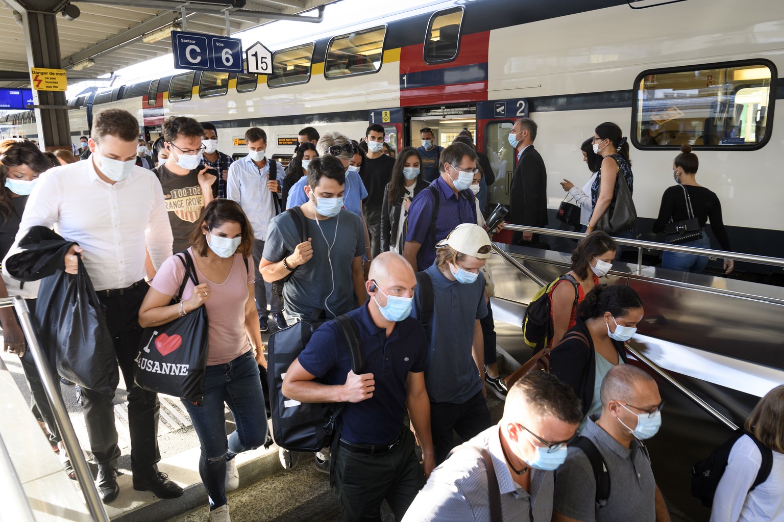 epa08529995 Passengers wearing face masks exit a train at a rail station in Lausanne, Switzerland, 06 July 2020. Swiss authorities have mandated the use of face masks, starting on 06 July, for all peo ...