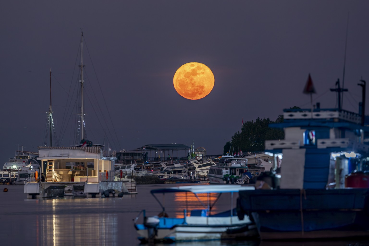 epa10830915 A rare Super Blue Moon appears in the night sky over Serangan Port in Bali, Indonesia, 31 August 2023. A 'Supermoon' occurs when the Moon comes to its closest point to the Earth. ...