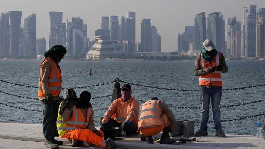 With the city skyline in the background, migrant workers work at the Doha port, in Doha, Qatar, Sunday, Nov. 13, 2022. Final preparations are being made for the soccer World Cup which starts on Nov. 2 ...