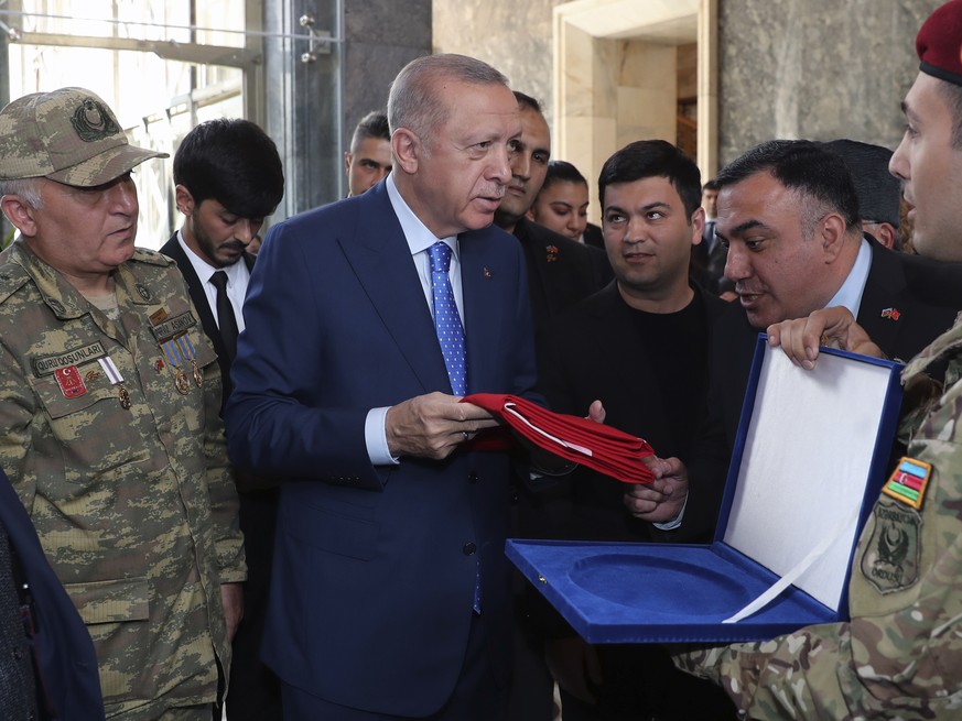 Turkish President Recep Tayyip Erdogan holds a national flag offered by Azerbaijani Turkish soldiers at the parliament, in Ankara, Turkey, Wednesday, May 18, 2022. Erdogan says NATO&#039;s enlargement ...