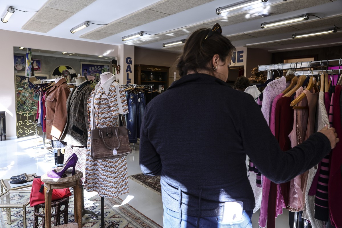 epa12355051 A woman searches through secondhand clothing on offer by the Neptune association in one of the stores that make up 'La Venelle' (The Alley), a solidarity village in Montreuil, Pa ...