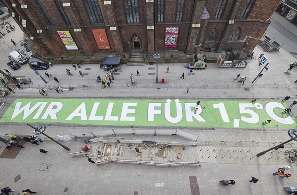 Activists from Fridays for Future stand around the lettering they painted &quot;we all for 1.5 degrees&quot; on Moenckebergstrasse in Hamburg, Germany, Friday, March 19, 2021. Fridays for Future Hambu ...