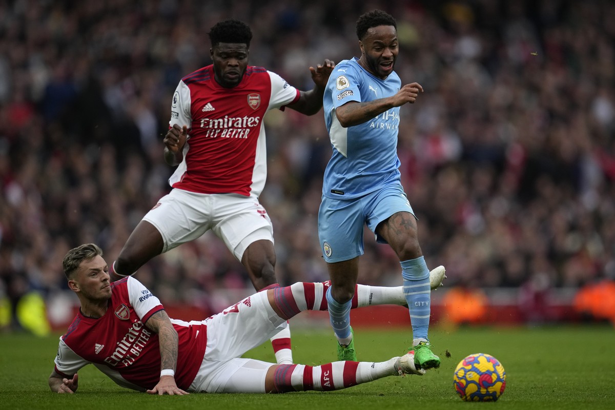 Arsenal's Ben White, down, and Arsenal's Thomas Partey challenge Manchester City's Raheem Sterling, right, during the Premier League soccer match between Arsenal and Manchester City at  ...