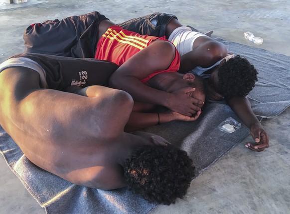 Rescued migrants rest on a coast some 100 kilometers (60 miles) east of Tripoli, Libya, Thursday, July 25, 2019. The U.N. refugee agency and the International Rescue Committee say up to 150 may have p ...