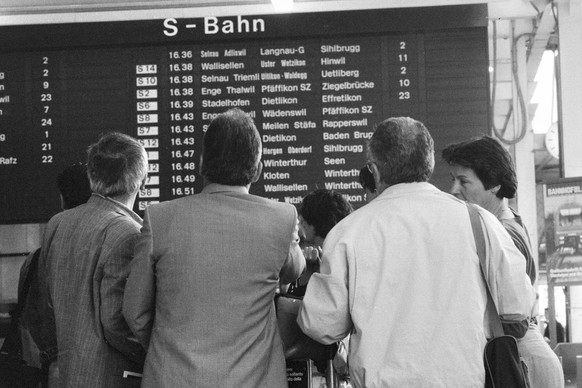 Reisende vor der Anzeigetafel am ersten Betriebstag der Zuercher S-Bahn im Hauptbahnhof Zuerich am 27. Mai 1990. (KEYSTONE/Str)