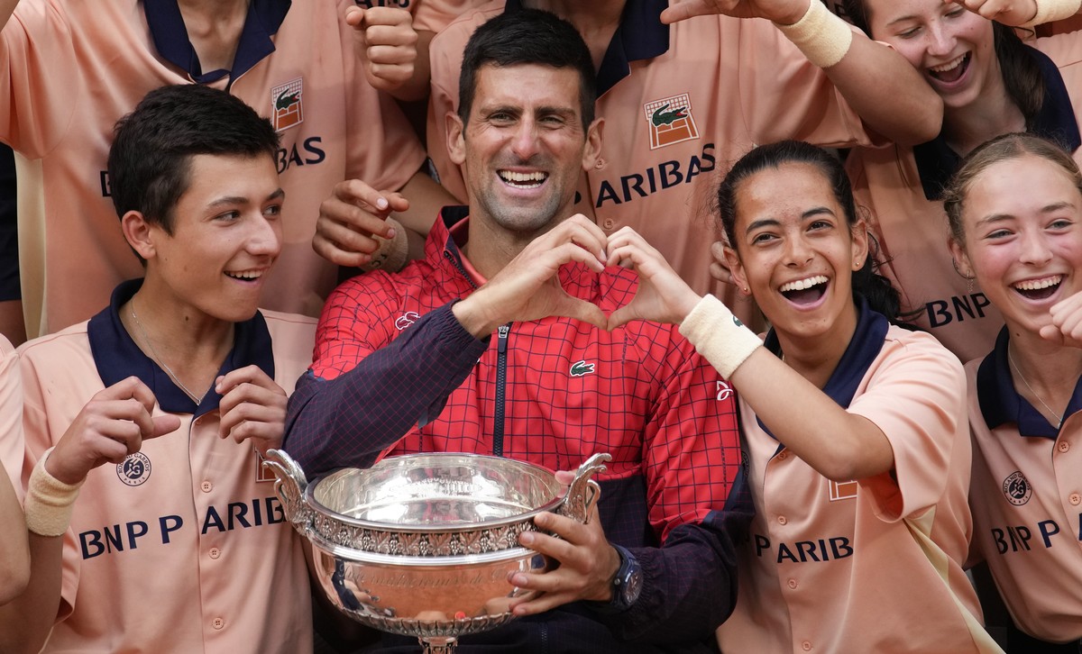 Serbia's Novak Djokovic poses with ball girls and boys as he celebrates winning the men's singles final match of the French Open tennis tournament against Norway's Casper Ruud in three  ...