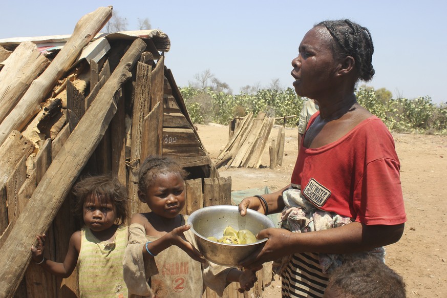 Toharano, mother of 18 children, with two of her children, holds a bowl in the village of Ankilimarovahatsy, Madagascar, Monday, Nov. 9, 2020. As a consequence of three straight years of drought, alon ...