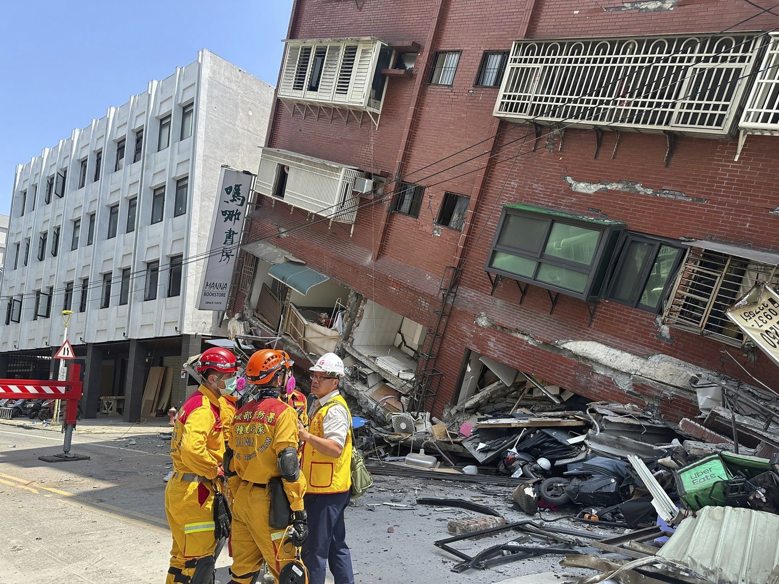 In this photo released by the National Fire Agency, members of a search and rescue team prepare outside a leaning building in the aftermath of an earthquake in Hualien, eastern Taiwan on Wednesday, Ap ...