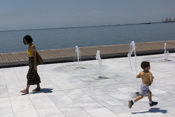 epa12222211 A child runs between fountains on a day with very high temperatures in Thessaloniki, Greece, 07 July 2025. Very high temperatures are forecast in Greece until 09 July. The highest temperat ...