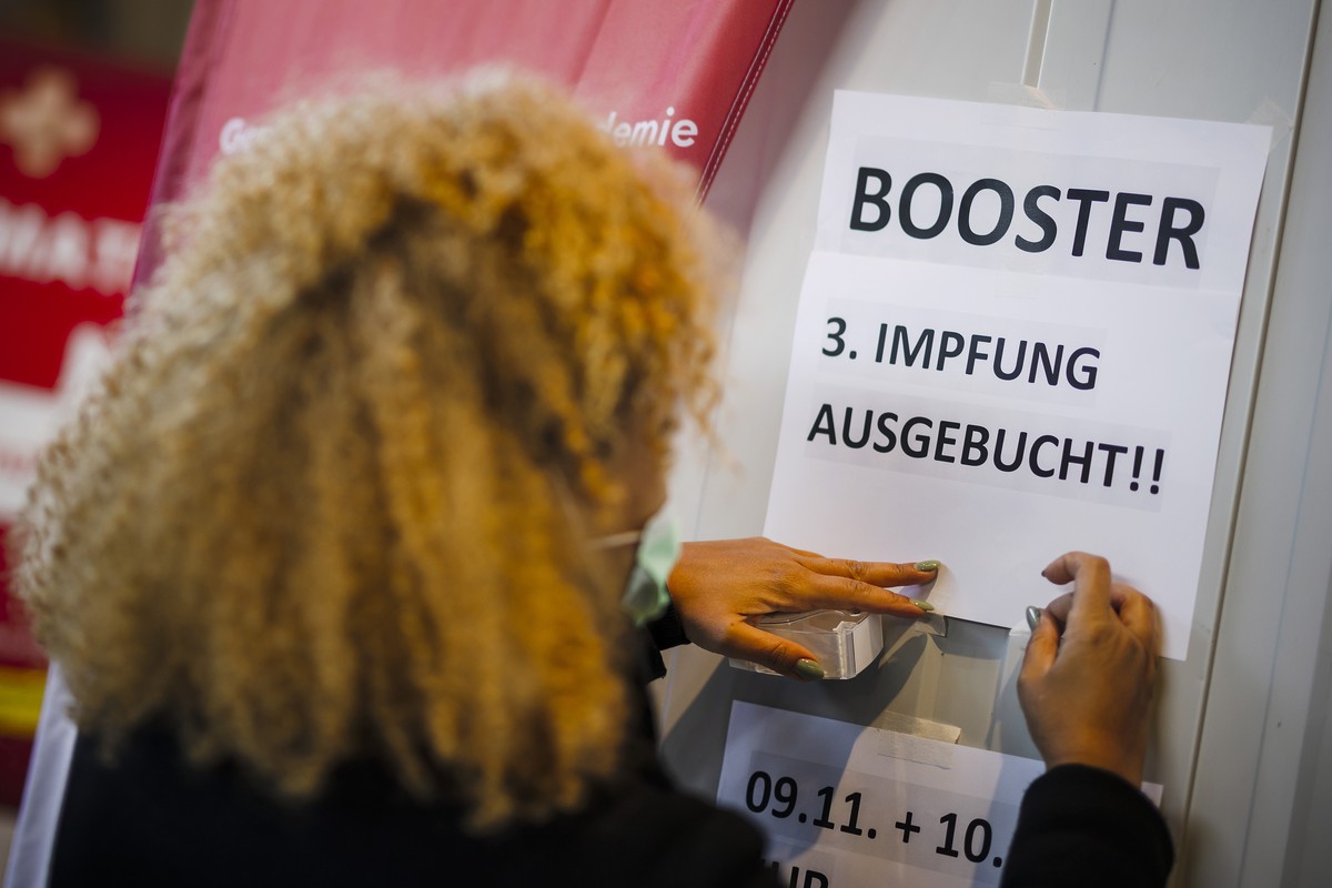 Eine Mitarbeiterin haengt Zettel mit der Aufschrift "Booster, 3. Impfung Ausgebucht" auf, beim Impfdorf in der grossen Halle des Hauptbahnhofs Zuerich, am Dienstag, 9. November 2021 in Zueri ...
