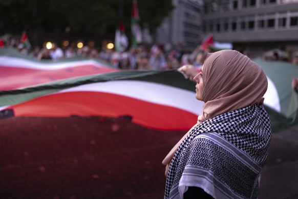 Mehrere Tausend Demonstranten halten waehrend einer genehmigten Demonstration in den Strassen von Zuerich Schilder und palaestinensische Flaggen, am Samstag, 23. August 2025, um ein sofortiges Ende de ...