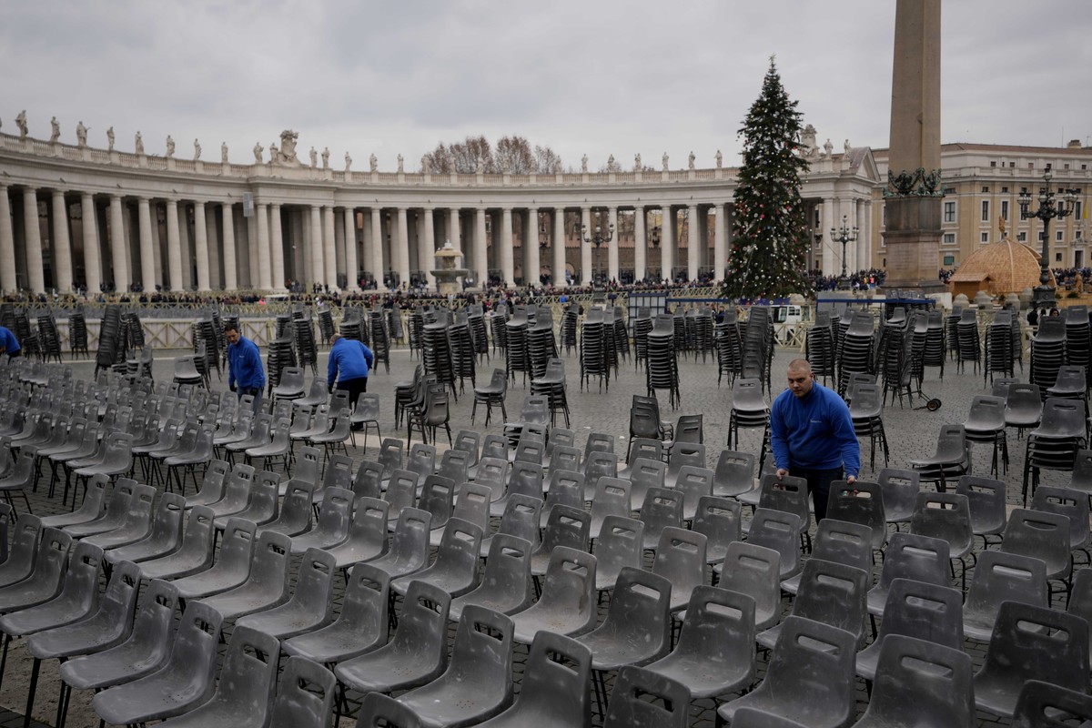 Workers set up chairs as people line up to enter Saint Peter's Basilica at the Vatican where late Pope Benedict XVI is being laid in state at The Vatican, Monday, Jan. 2, 2023. Benedict XVI, the  ...