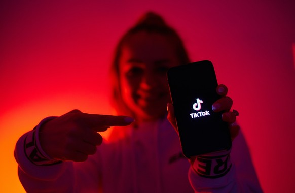 Junge Frau mit Tiktok-App auf dem Smartphone.