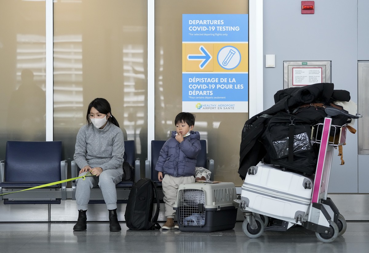 A family waits to travel to the United States of America at Pearson International Airport during the COVID-19 pandemic in Toronto, Friday, Dec. 3, 2021. New travel testing and restrictions have been p ...