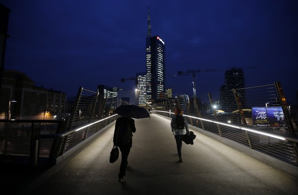 People walk on a bridge which leads to business center and the Unicredit headquarters building, center, in Milan, Italy, Tuesday, Nov. 11 , 2014. The recent Europe-wide health check on banks is produc ...