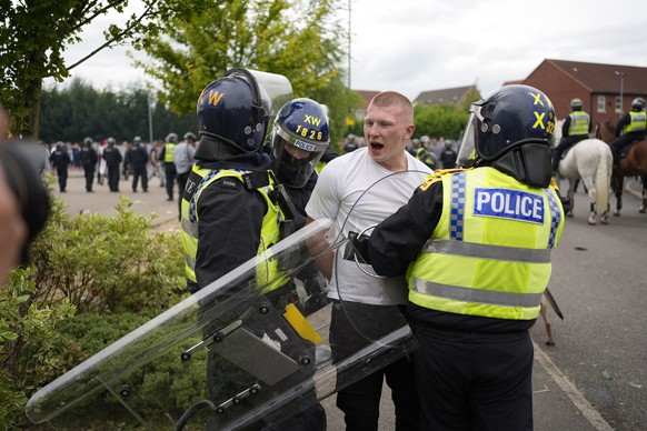 Police officers lead a man away during an anti-immigration demonstration outside the Holiday Inn Express in Rotherham, England, Sunday Aug. 4, 2024. (Danny Lawson/PA via AP)