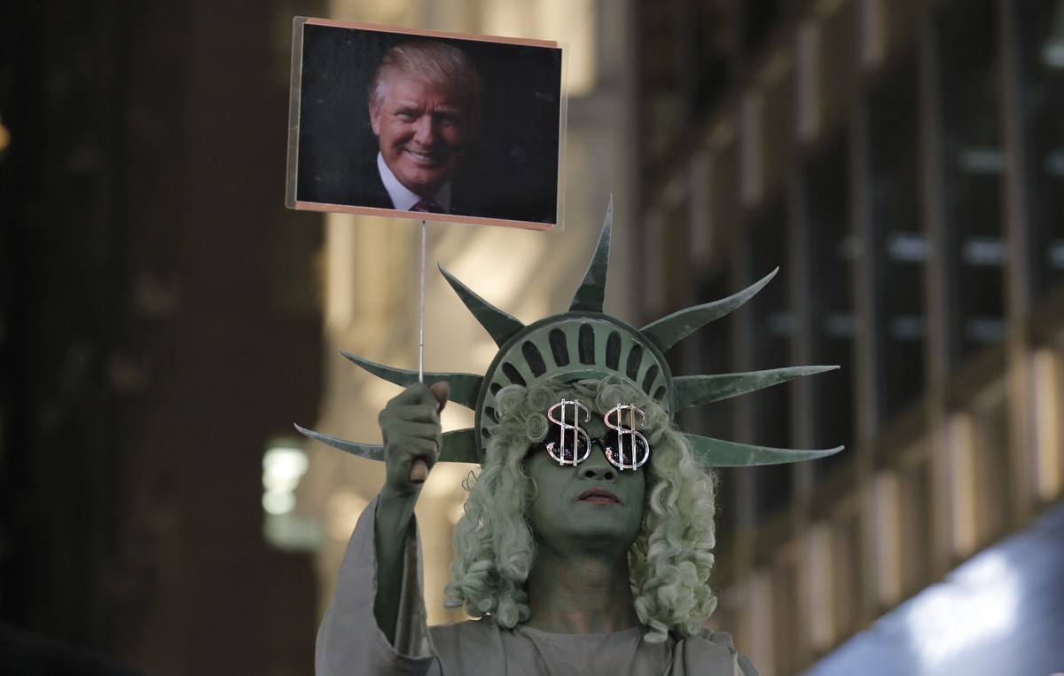 A street performer dressed as the Statue of Liberty holds up a picture of U.S. President-elect Donald Trump in Hong Kong's downtown, Wednesday, Nov. 9, 2016. Around the world, people reacted with ...