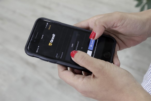 FILE - A woman looks at the Grindr app on her mobile phone in Beirut, Lebanon, May 29, 2019. Norway���s data privacy watchdog fined gay dating app Grindr $7.16 million for sending sensitive personal d ...