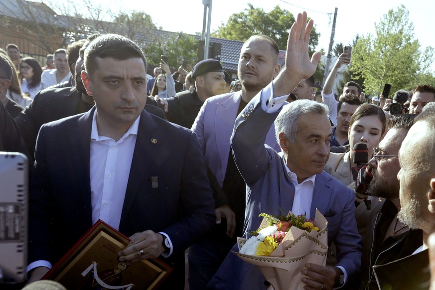 epa12072496 Banned presidential candidate Calin Georgescu waves to supporters as he walks with leader of far-right party Alliance for the Union of Romanians (AUR) George Simion after casting their bal ...