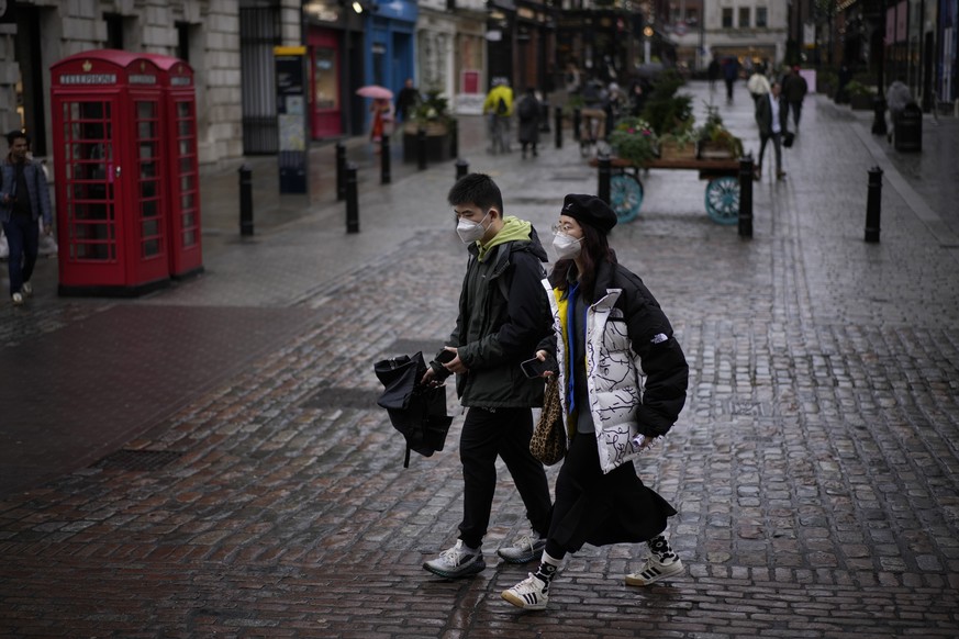 People wearing face masks to curb the spread of coronavirus walk through the Covent Garden district of central London, Tuesday, Jan. 11, 2022. British Prime Minister Boris Johnson faced more allegatio ...