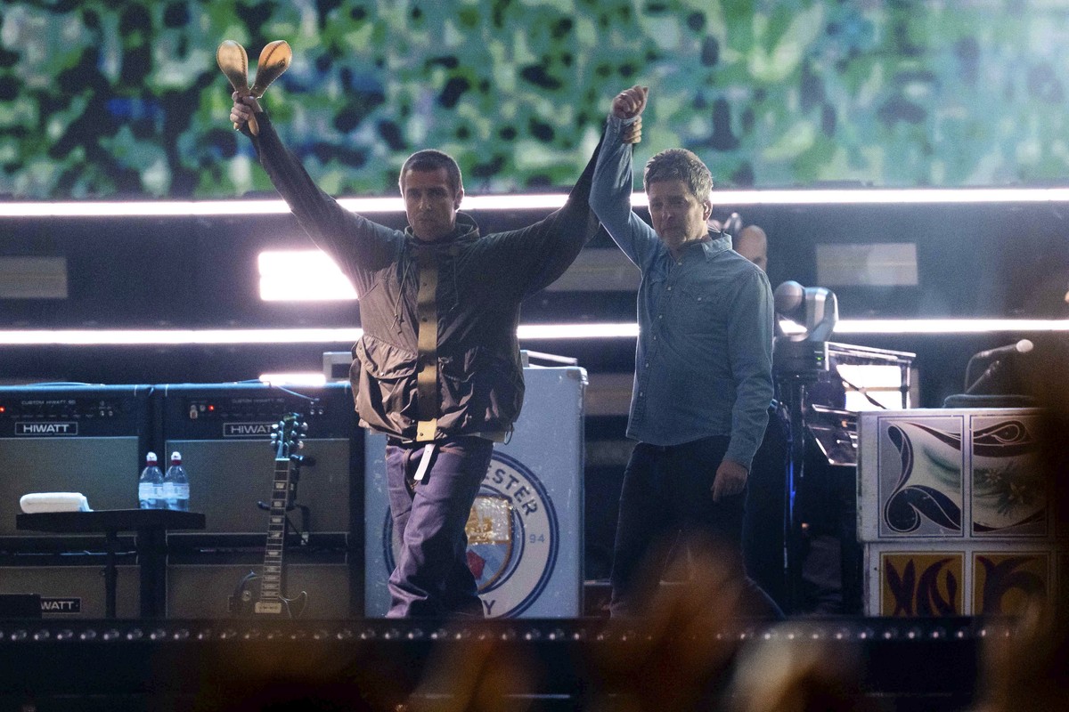 Liam Gallagher, left, holds the hand aloft of Noel Gallagher from the band Oasis as they perform during their reunion concert on Friday, July 4, 2025, in Cardiff. (Photo by Scott A Garfitt/Invision/AP ...