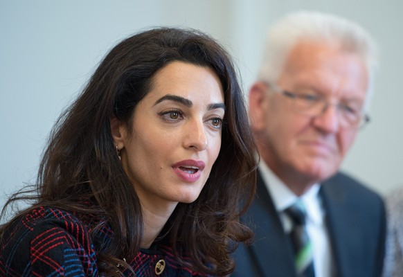 epa05536754 British human rights attorney Amal Clooney (L) and Premier of federal state Baden-Wuerttemberg Winfried Kretschmann (R) speak to the press at state ministry in Stuttgart, Germany, 12 Septe ...