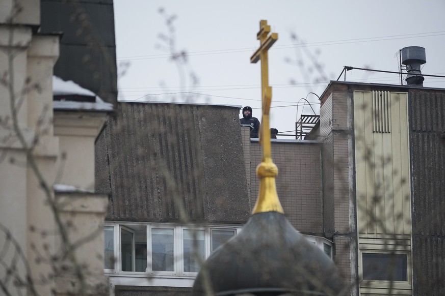 Police officers stand guard on a roof of an apartment building near the Church of the Icon of the Mother of God, in Moscow, Russia, Friday, March 1, 2024. Relatives and supporters of Alexe…