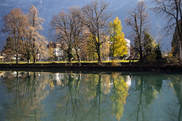 Personen schreiten der Aare entlang und geniessen das schoene Wetter und die milden Temperaturen, am Sonntag, 15. November 2020, in Interlaken. (KEYSTONE/Peter Schneider)