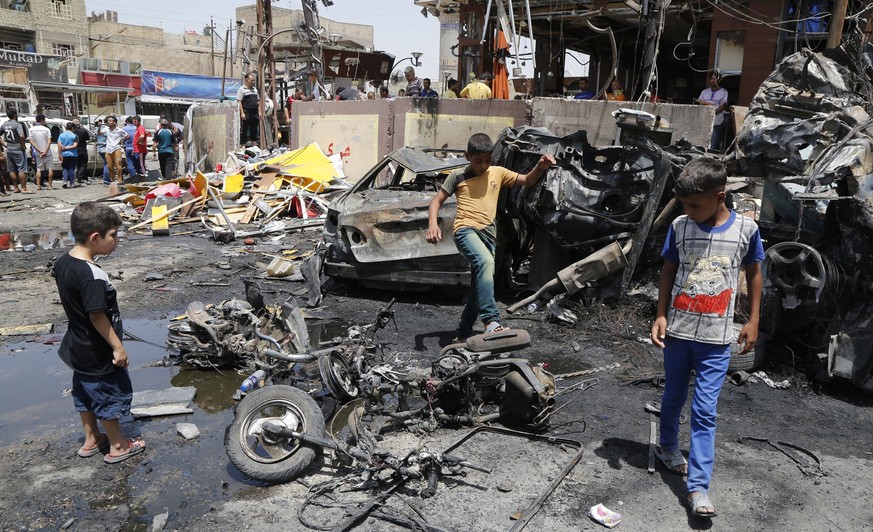 Ein paar Jungs betrachten den Ort, an dem eine Autobombe explodiert ist.