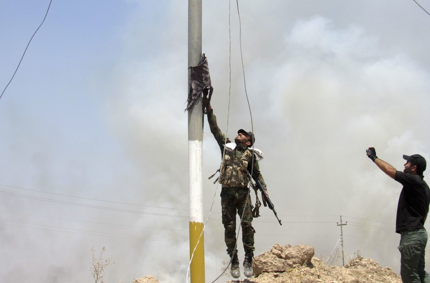 A fighter with Badr Brigades Shiite Popular Mobilization Forces takes down a flag of the Islamic State group outside in Fallujah, 40 miles (65 kilometers) west of Baghdad, Iraq, Monday, May 23, 2016.  ...