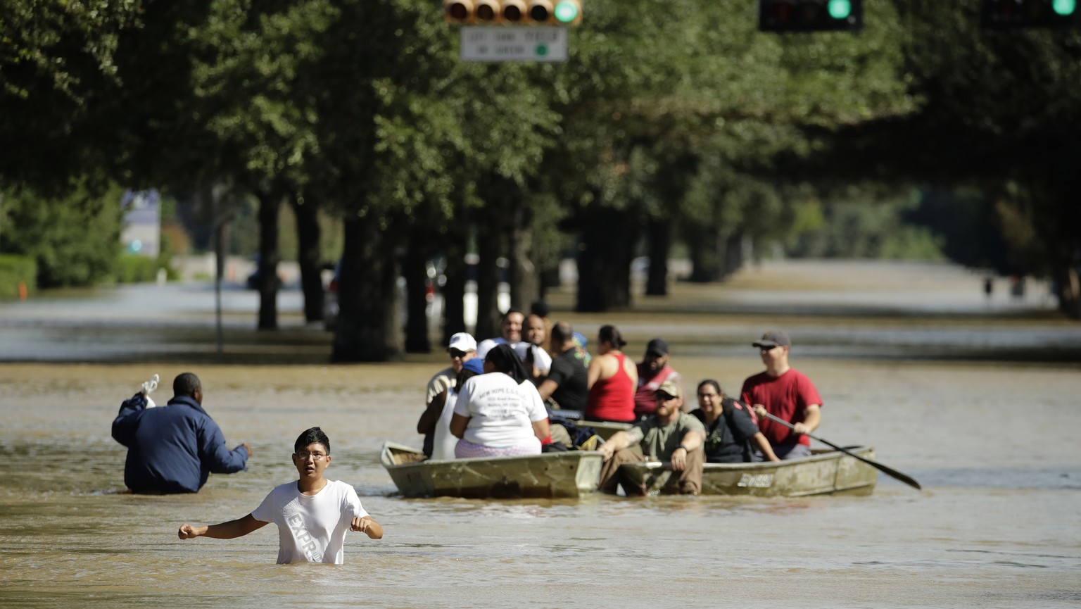 FILE - In this Wednesday, Aug. 30, 2017, file photo, people evacuate a Houston neighborhood inundated after water was released from nearby Addicks Reservoir when it reached capacity due to Tropical St ...