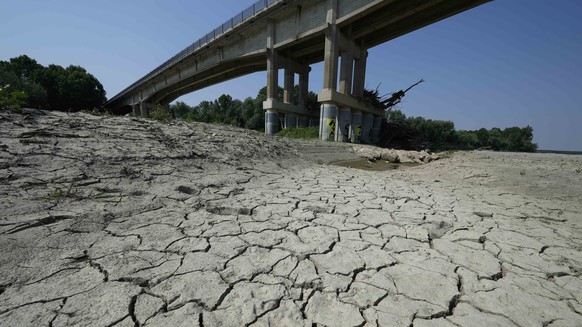 FILE - Dry cracked land is visible under a bridge in Boretto on the bed of the Po river, Italy, Wednesday, June 15, 2022. The mayor of Milan signed an ordinance Saturday, June 25, 2022, turning off pu ...