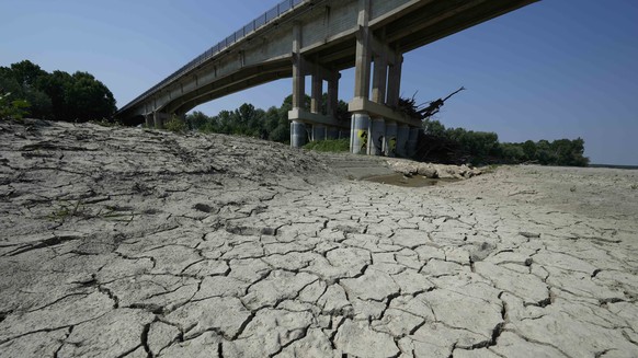 FILE - Dry cracked land is visible under a bridge in Boretto on the bed of the Po river, Italy, Wednesday, June 15, 2022. The mayor of Milan signed an ordinance Saturday, June 25, 2022, turning off pu ...