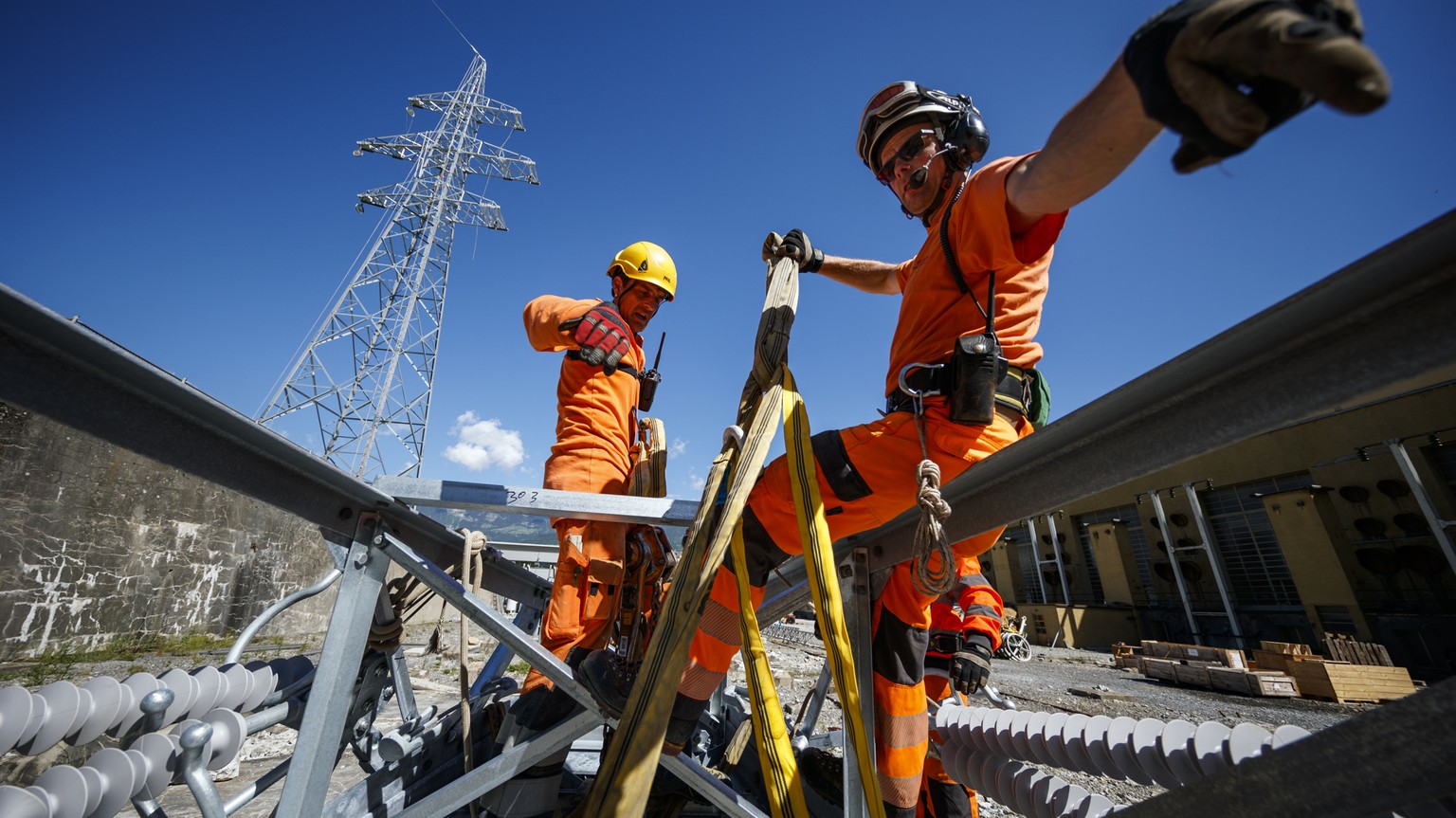 Staff members prepare an electric pylon element prior to attaching it to the hook of a Super Puma utility helicopter during construction operations of a new Swissgrid 220 kV aerial electric line in th ...