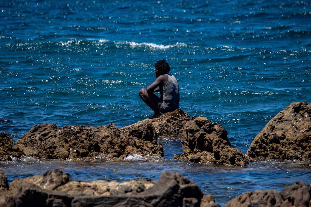 KEYPIX - A migrant who crossed into Spain from Morocco sits on a shore in the Spanish enclave of Ceuta, Sunday, Aug. 2, 2026. (KEYSTONE/AP Photo/Antonio Sempere)