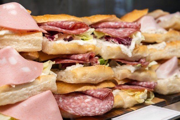 traditional Italian panini sandwich with ciabatta bread with truffle sauce, salami, mortadella sausage, prosciutto and cheese. takeaway, traditional Italian fast food