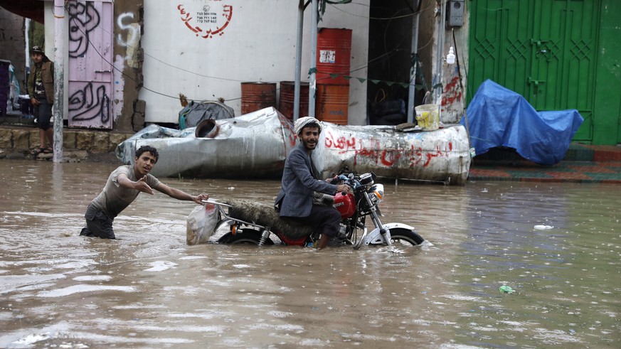 epaselect epa10101764 Yemenis try to get a broken down motorcycle out of a flooded street following a heavy rainfall in Sana&#039;a, Yemen, 01 August 2022. Torrential rains and associated floods have  ...