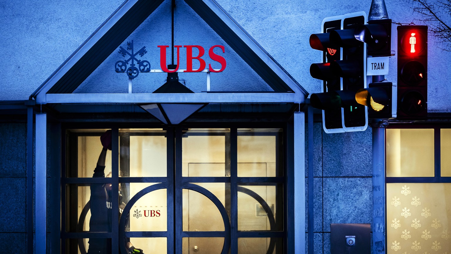 Ein Mann reinigt den Eingangsbereich einer UBS Filiale in Zuerich Hoengg, am Montag, 5. Februar 2024 in Zuerich. Die Grossbank UBS wird am Dienstag die Zahlen f