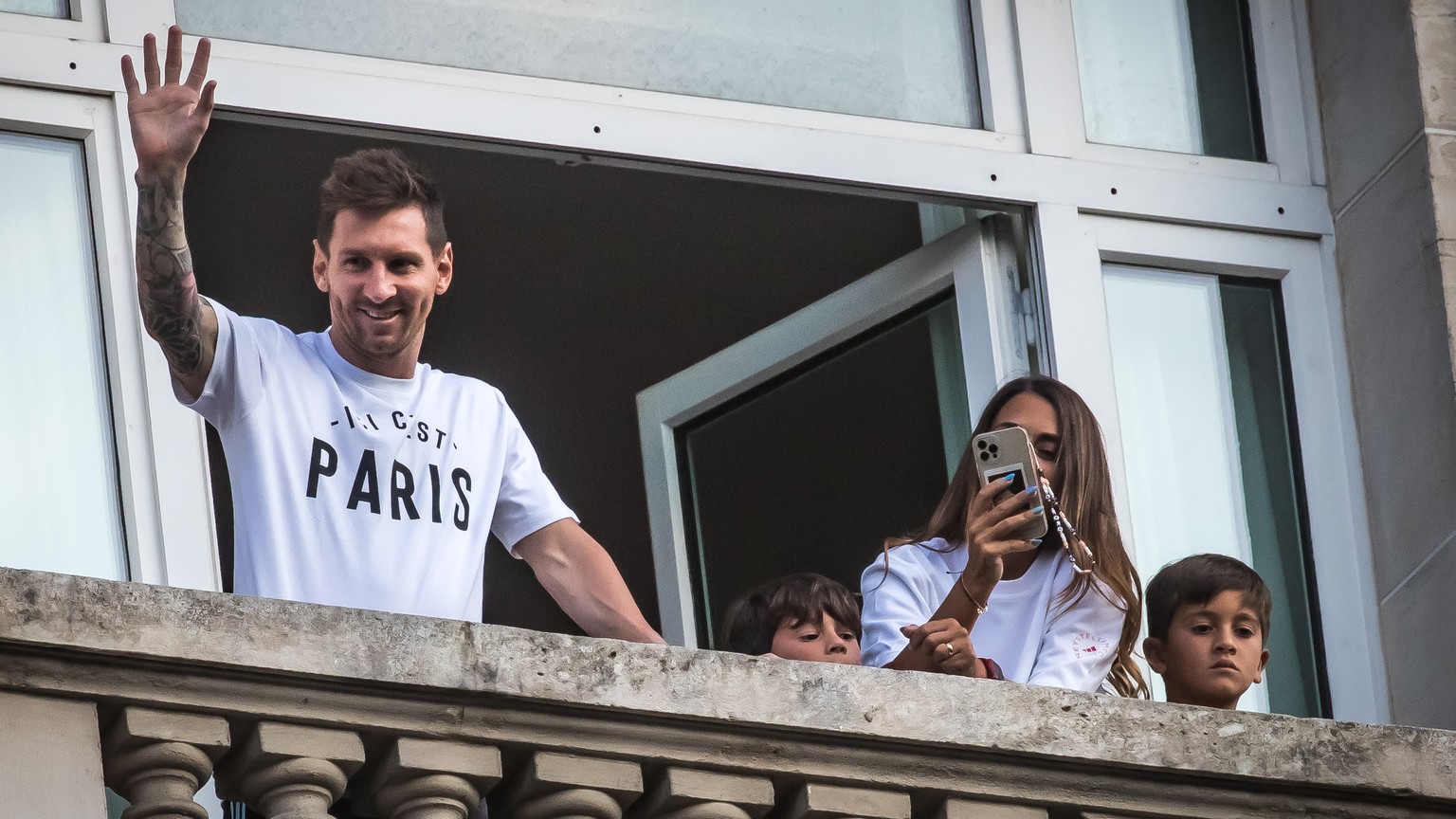 epa09408729 Argentinian striker Lionel Messi greets his supporters from a window of the &#039;Royal Monceau&#039; hotel in Paris, France, 10 August 2021. Messi arrived to Paris to sign a contract with ...