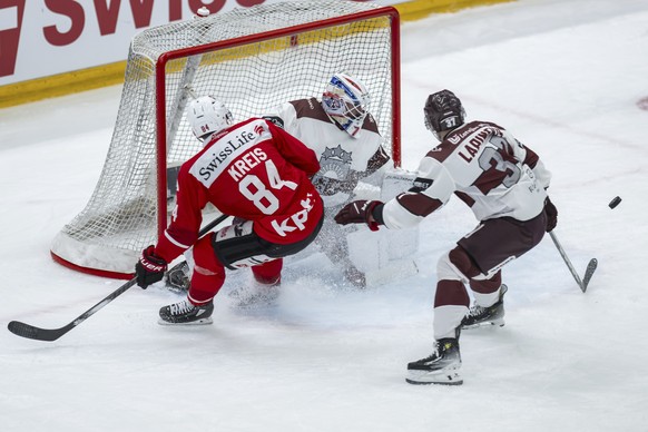 Switzerland&#039;s Samuel Kreis, left, in action against Latvia&#039;s Oskars Lapinskis, right, and goalkeeper Ivars Punnenovs during an ice hockey World Cup preparation match between Switzerland and  ...