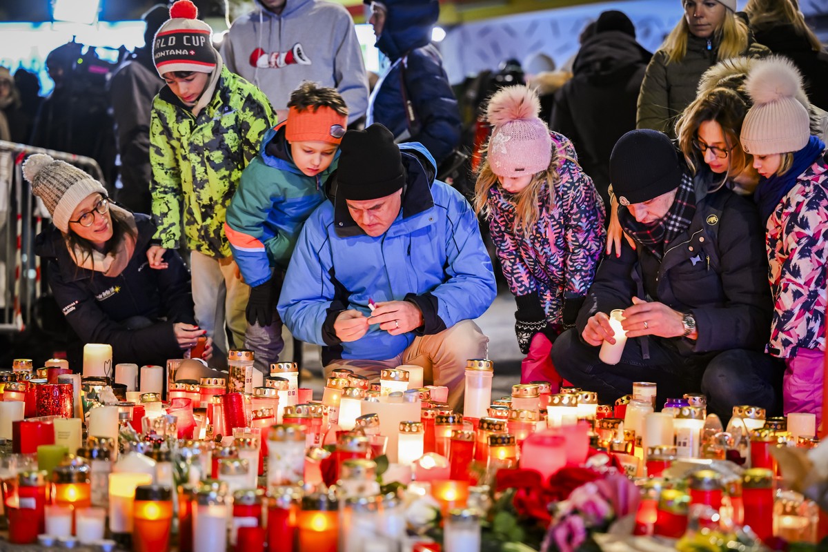 epa12621912 People pay their respects to the victims with flowers and candles near the area where a fire broke out during the New Year's celebrations in Crans-Montana, Switzerland, 02 January 202 ...