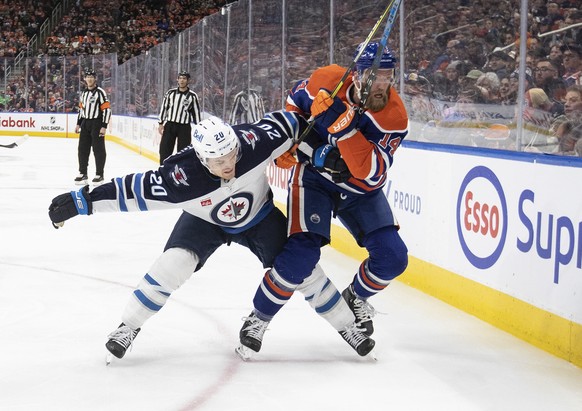 Winnipeg Jets&#039; Karson Kuhlman (20) and Edmonton Oilers&#039; Mattias Ekholm (14) battle for the puck during the second period of an NHL hockey game Friday, March 3, 2023, in Edmonton, Alberta. (J ...