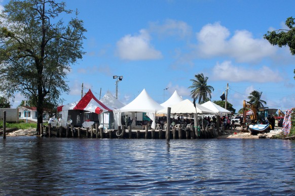 epa13129368 People under tents await the identification of the bodies after the MV Barima ferry sinking in Charity, Guyana, 22 July 2026 (issued 23 July 2026). Guyanese authorities reported that the n ...