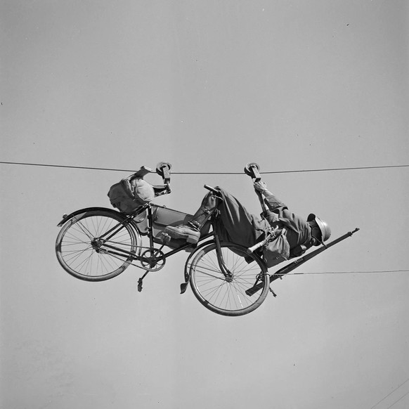 Radfahrer mit Rad auf einer Tyrolienne (Seilrutsche), um 1935, Foto von Karl Egli.